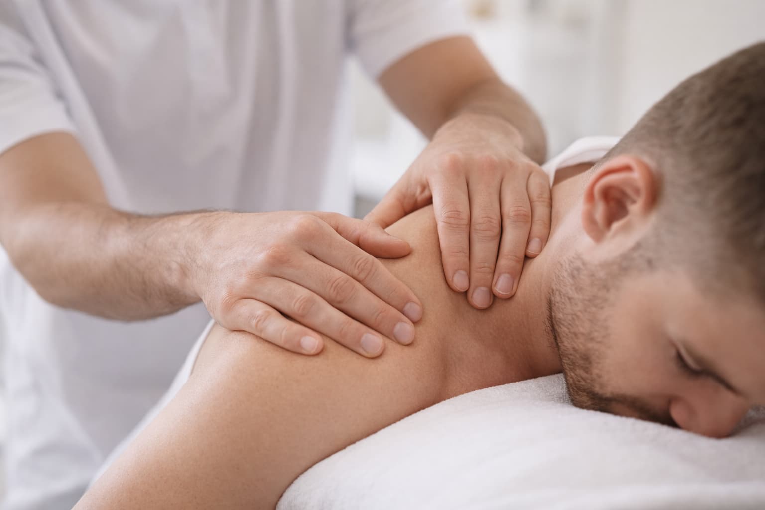 Manos del fisioterapeuta realizando una técnica suave en el hombro